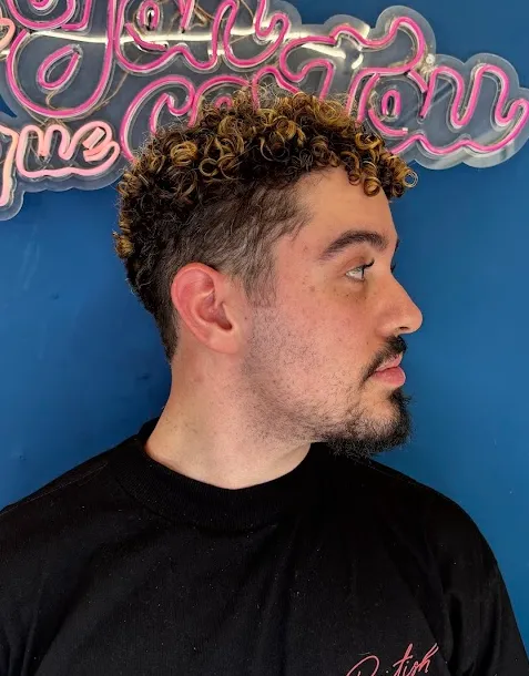 Undercut Cacheado Lateral — Vista lateral de undercut em cachos com luzes mel. Design que valoriza a curvatura superior. no Studio do Jon em Belo Horizonte